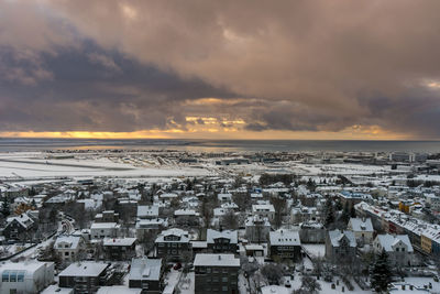 Aerial view of townscape against cloudy sky during winter at sunset