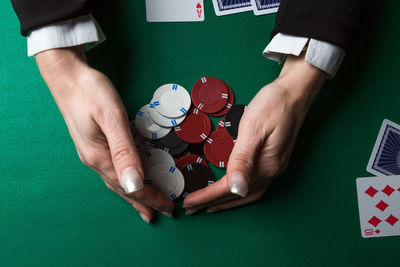 Cropped hands of woman collecting gambling chips on table