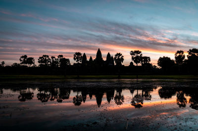 People at beach against sky during sunset