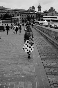 Rear view of woman walking on footpath in city