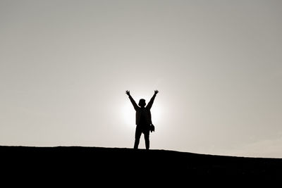 Silhouette man standing on field against sky during sunset