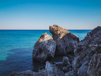 Rocks on beach against clear blue sky