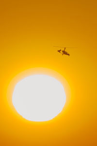 Low angle view of airplane flying in sky during sunset