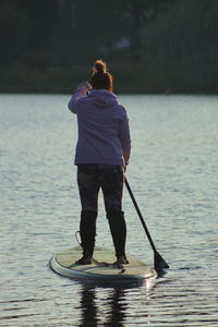 Rear view of woman paddleboarding in lake