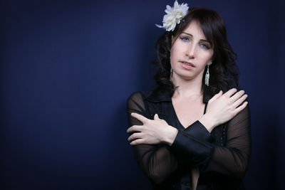 Portrait of woman standing against black background