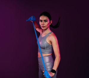 Portrait of young woman standing against black background