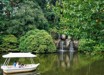 People sitting by lake against trees