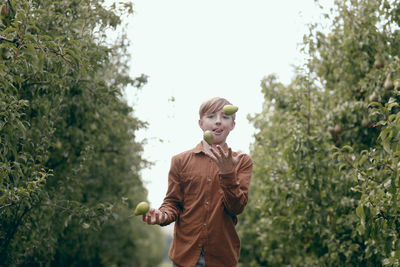 Boy juggles pear fruits while playing in orchard
