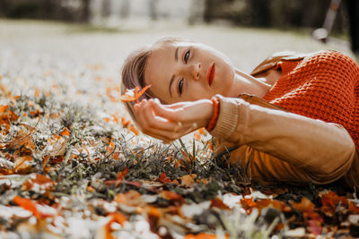 Portrait of young woman lying on field during autumn