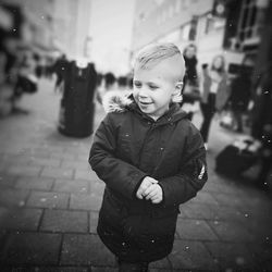 Full length of boy standing on street in rain