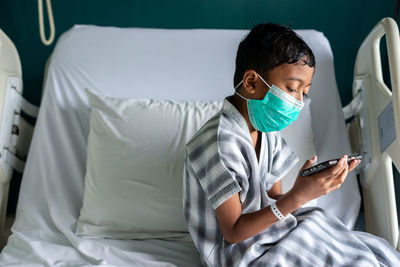 Young man using mobile phone while sitting on bed