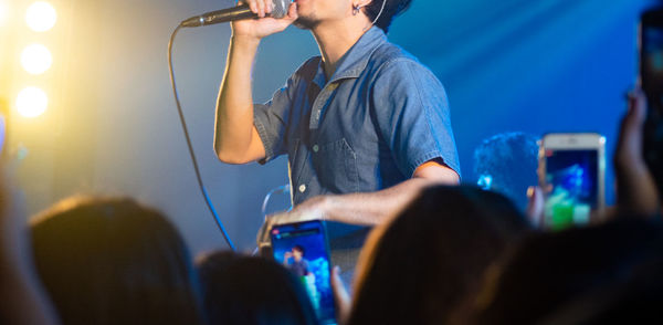 Midsection of man singing during concert