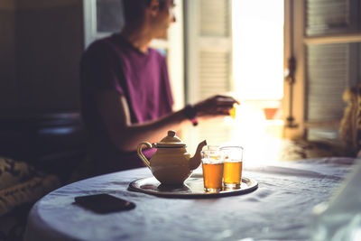 Midsection of woman holding drink in glass on table