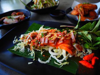Closeup thai food traditional with salmon spicy, chicken, pork, papaya salad in black plate on table