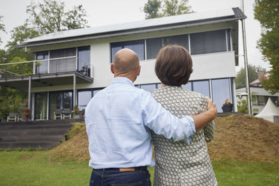 Senior couple standing together in front of house
