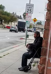 Man sitting on sidewalk in city