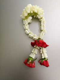 Close-up of roses and jasmine garland against white background