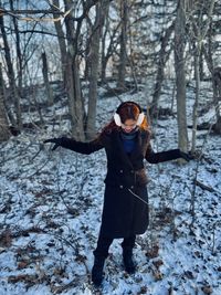 Full length of woman standing in a snowy forest