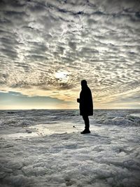 Silhouette man standing on beach against sky during sunset