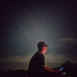 Low angle view of young man against sky at night