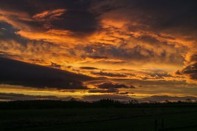 Scenic view of dramatic sky over land during sunset