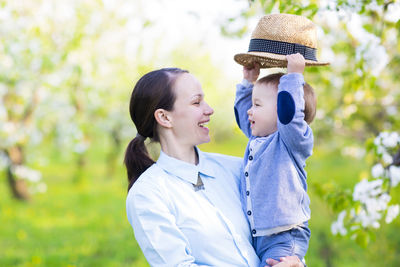 Smiling mother and son with hat outdoors