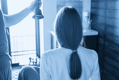 Rear view of woman looking through window