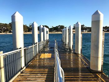 Pier over sea against clear blue sky