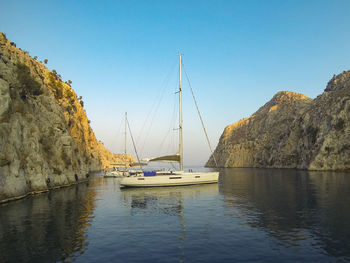 Sailboats moored on sea against clear sky