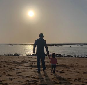 People on beach against sky during sunset