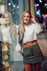 Portrait of smiling young woman standing on street in city