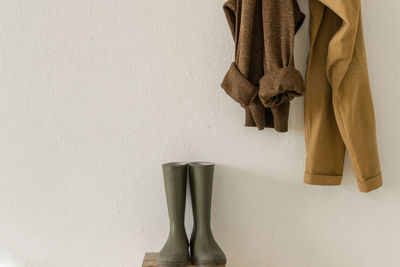 Close-up of clothes hanging over rubber boots against wall