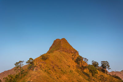 Low angle view of rocks against clear blue sky