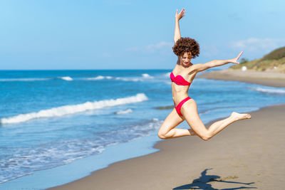 Full length of woman jumping at beach