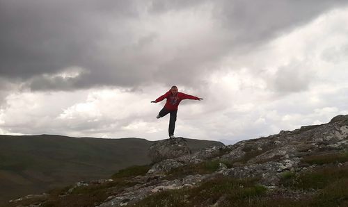 Man standing on rock at mountain against sky