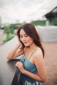 Young woman smiling while standing against blurred background