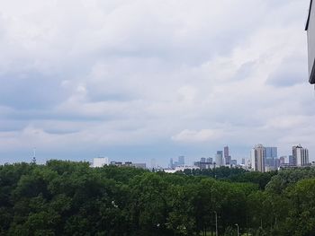 Trees and cityscape against sky