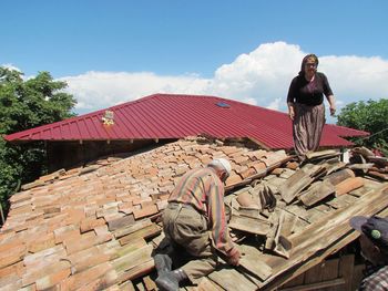 Full length of man sitting on roof against sky