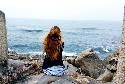 Rear view of woman overlooking calm sea