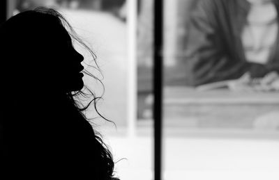 Rear view of woman looking through window