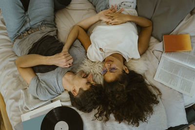 High angle view of couple lying with each other on bed at home