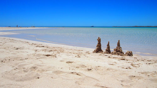 Scenic view of beach against clear blue sky