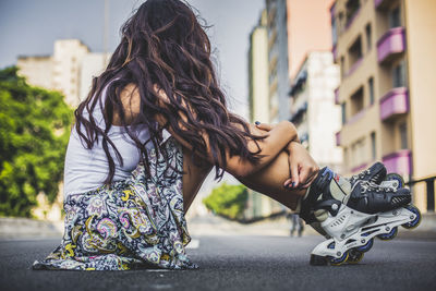 Rear view of woman sitting on road