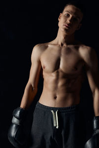 Portrait of young man standing against black background