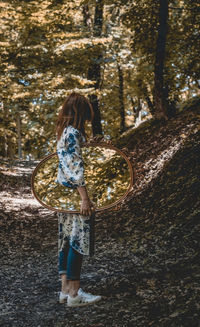 Rear view of woman standing by tree in forest