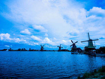 Traditional windmills by lake against sky at night