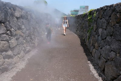 People walking on walkway amidst stone wall