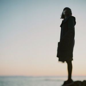 Woman standing by sea against clear sky