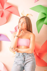 Portrait of young woman standing against wall