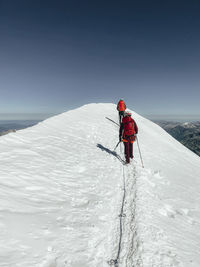 Two climbers ascending mont blanc on a glacier under blue sky